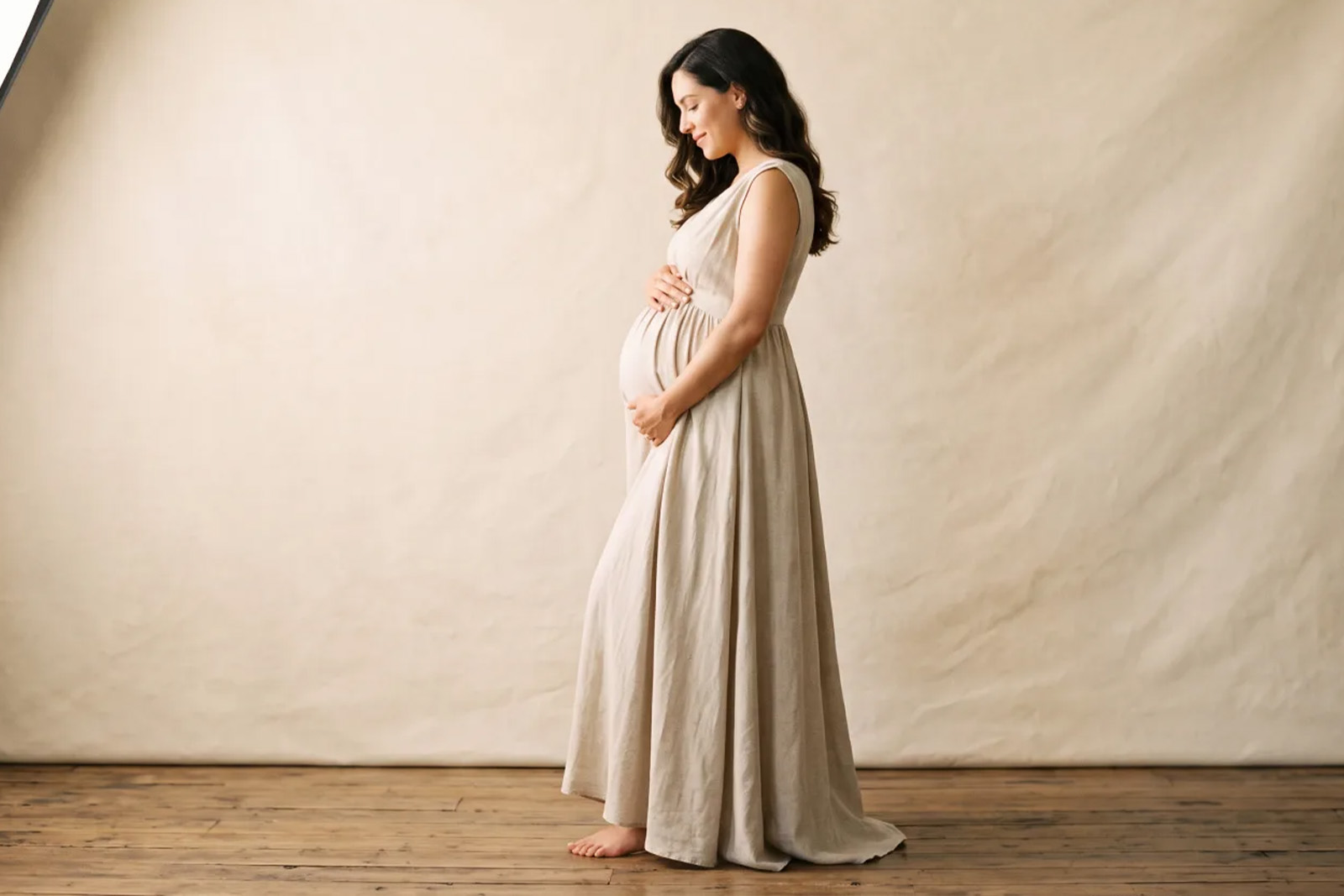 Expectant mother in a flowing gown photographed on a portable studio set at home