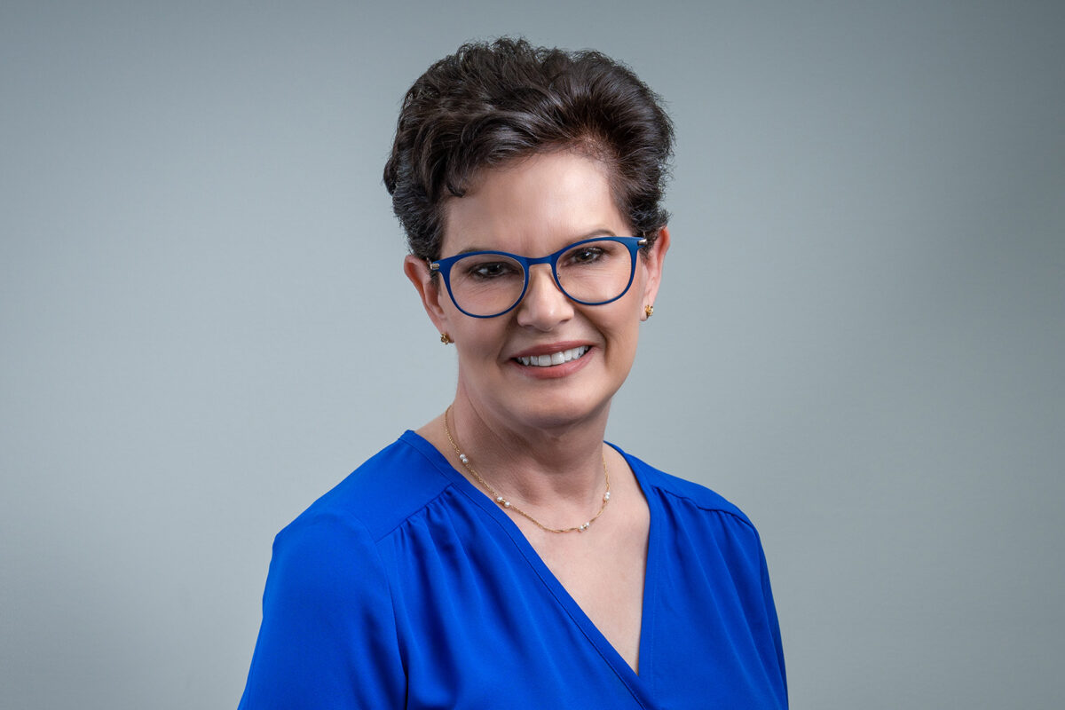Woman with short red hair in a blue top smiling for a headshot