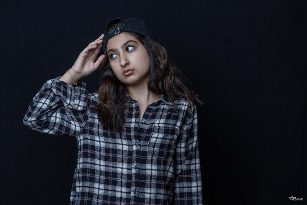 Young woman in a plaid shirt posing against a dark backdrop