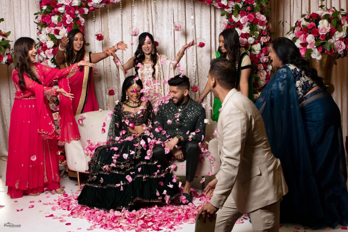 Couple seated on a decorated stage at a South Asian celebration