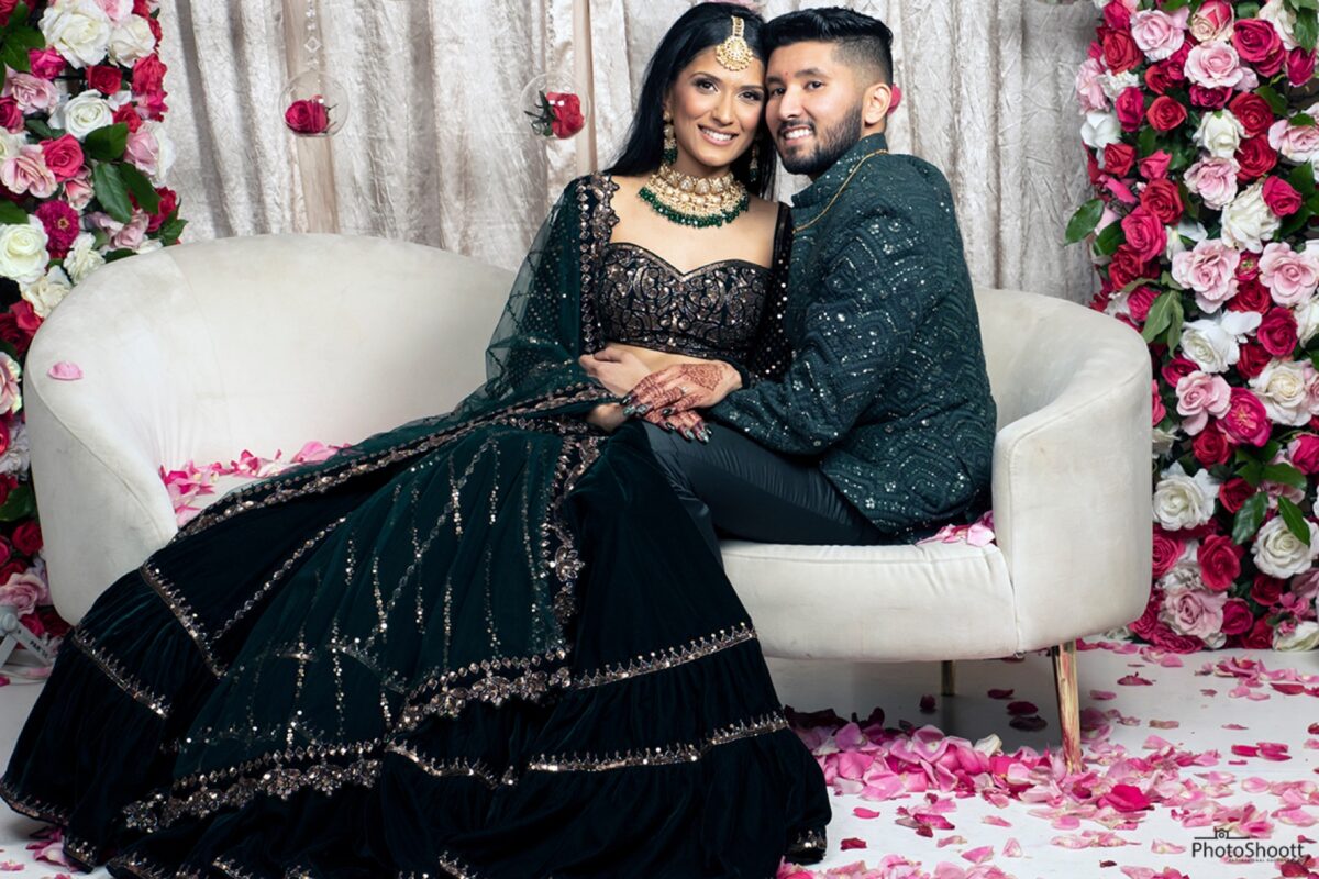 Couple in traditional dress posing on a white sofa at their celebration