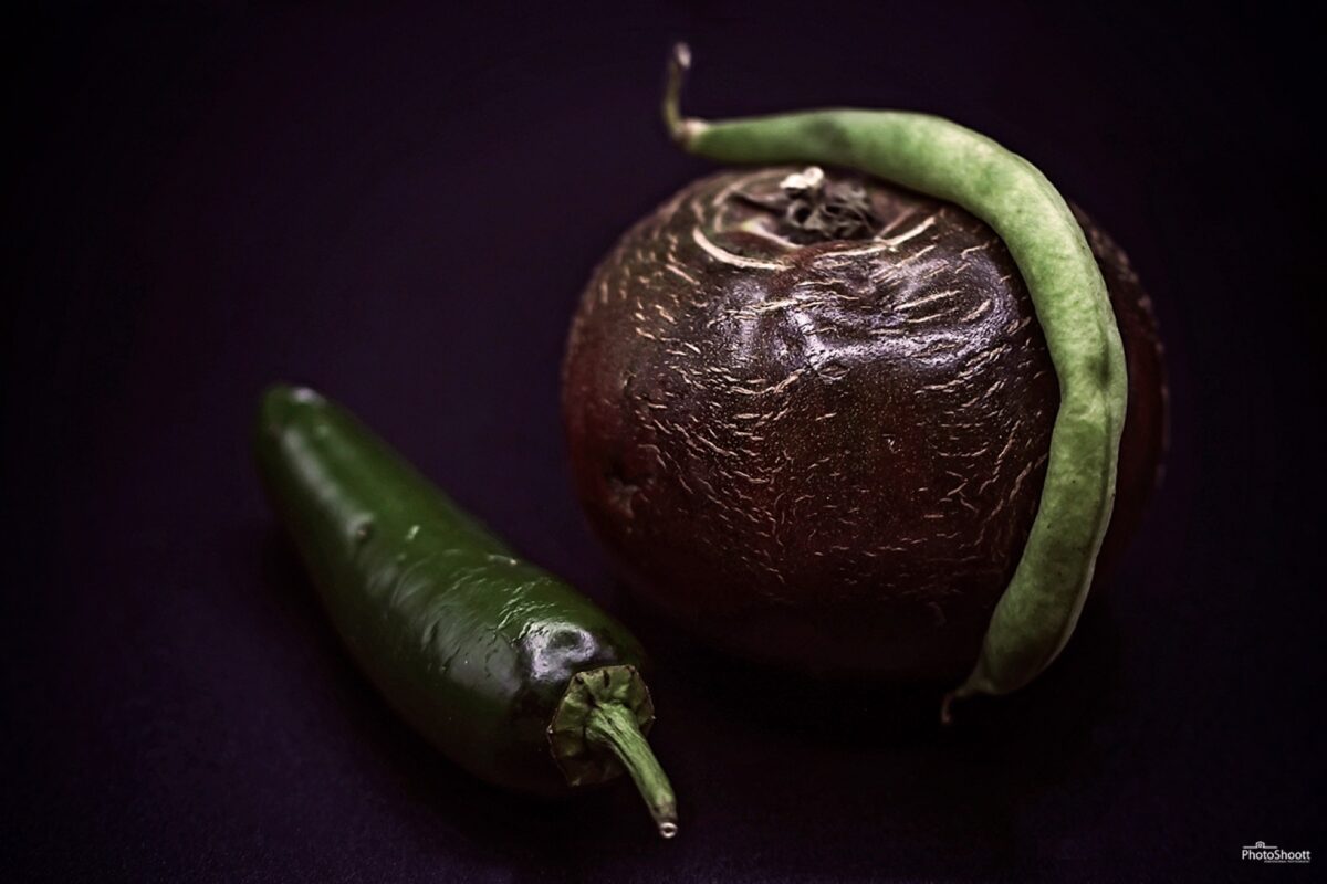 Dark still life of a pomegranate and chili pepper