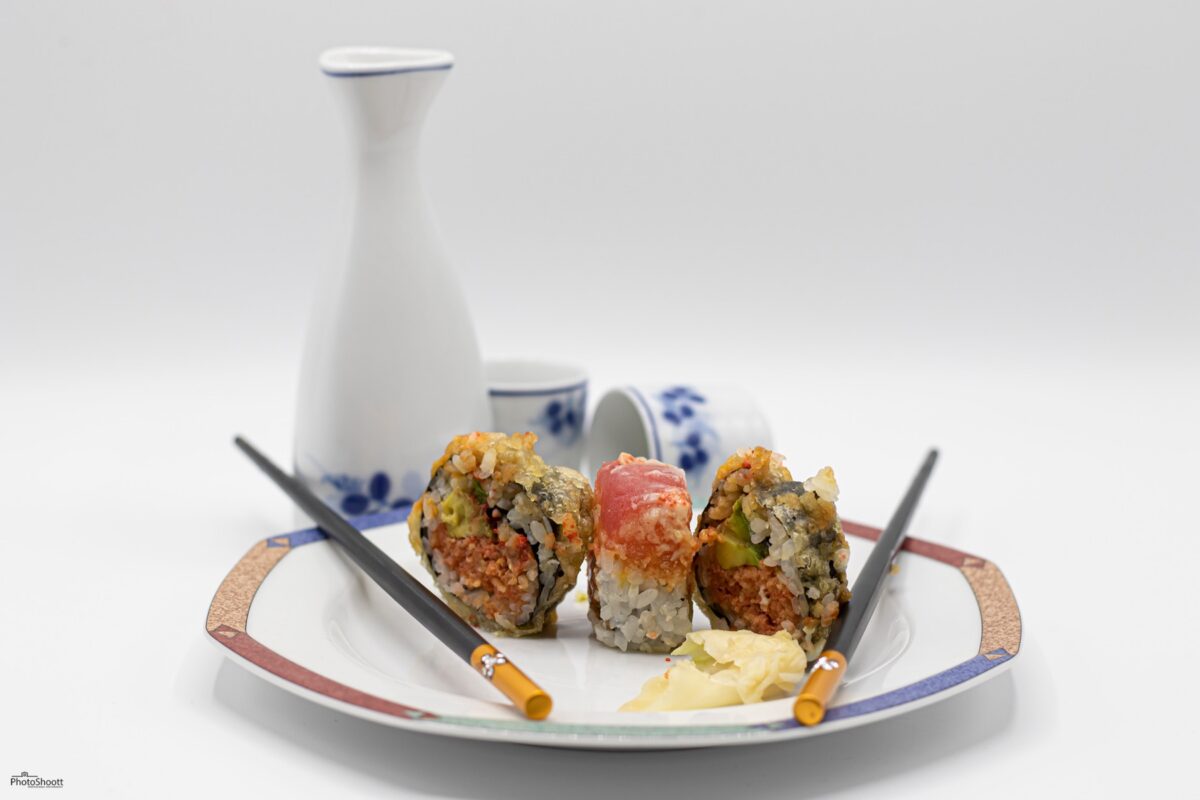 Sushi rolls with a sake set on a white plate