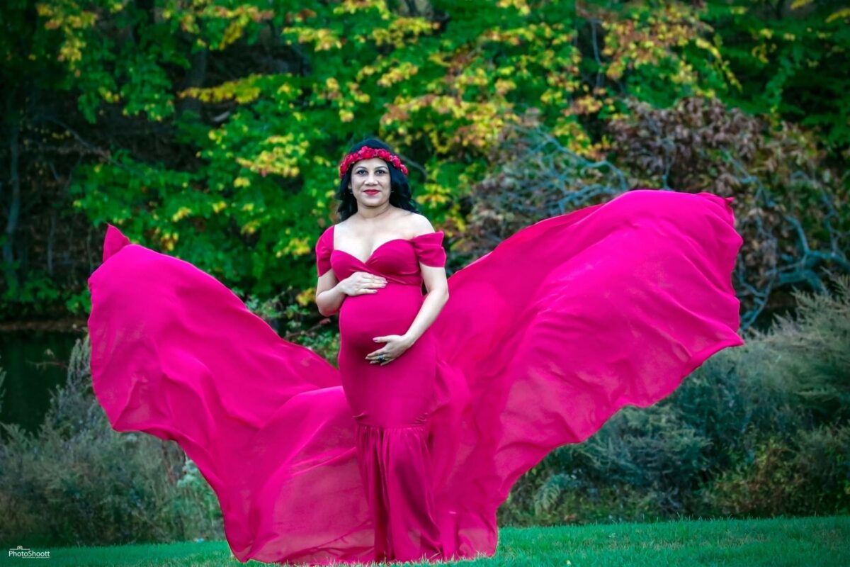Expectant mother in a flowing pink gown outdoors