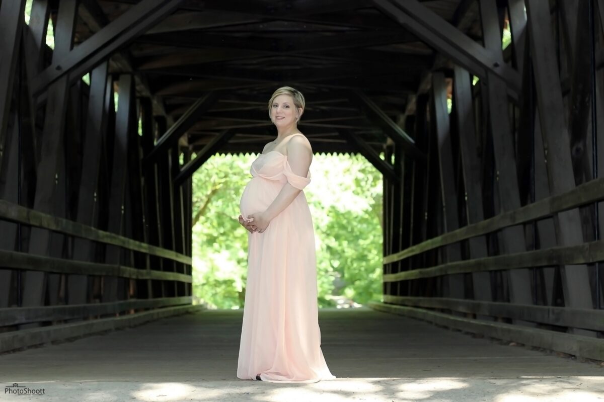 Expectant mother standing in a covered wooden bridge
