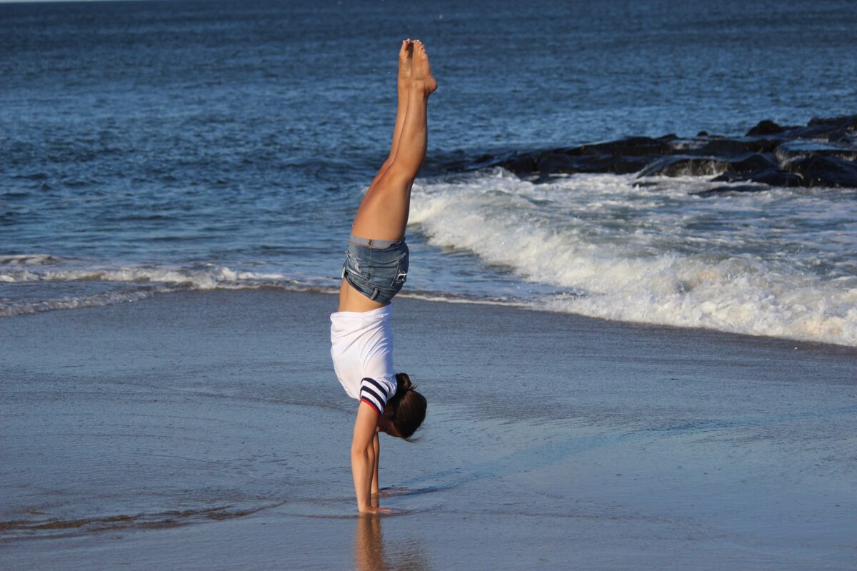 Woman doing a handstand at the water's edge on the beach