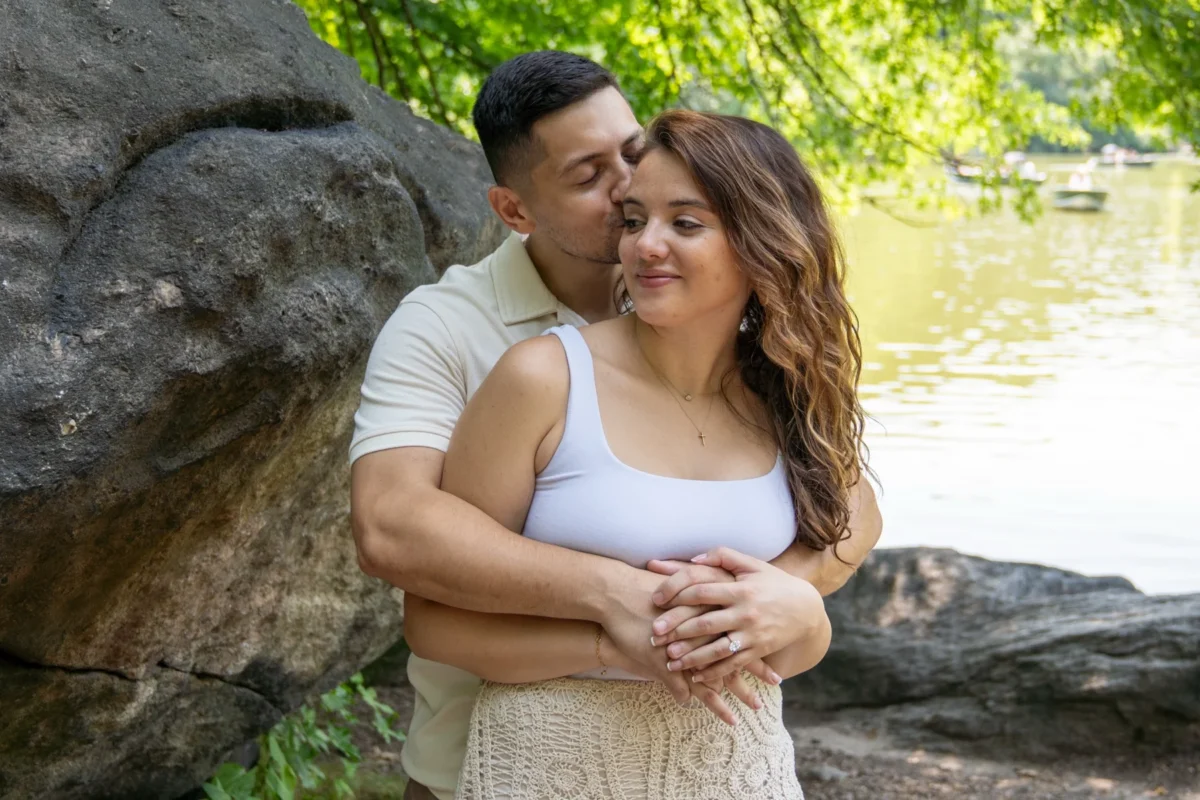 Engaged couple embracing on a park bench under the trees