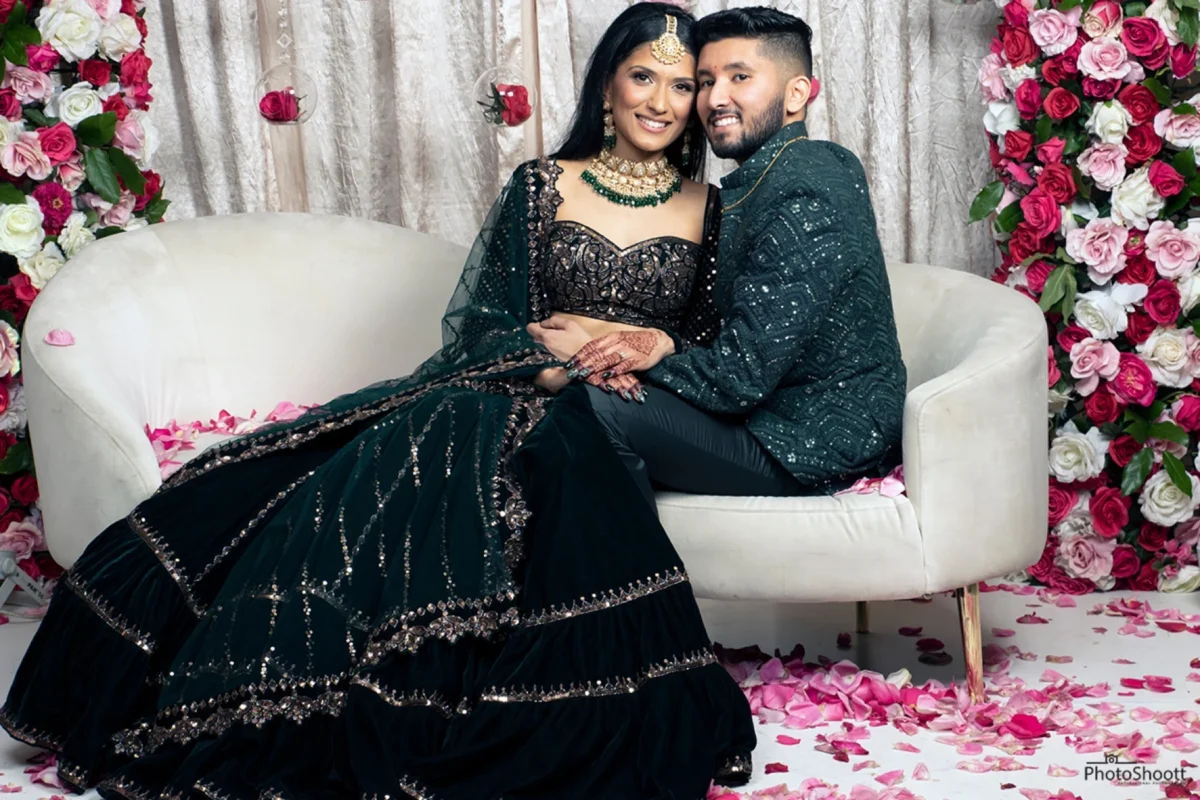Couple in traditional dress posing on a white sofa at their celebration