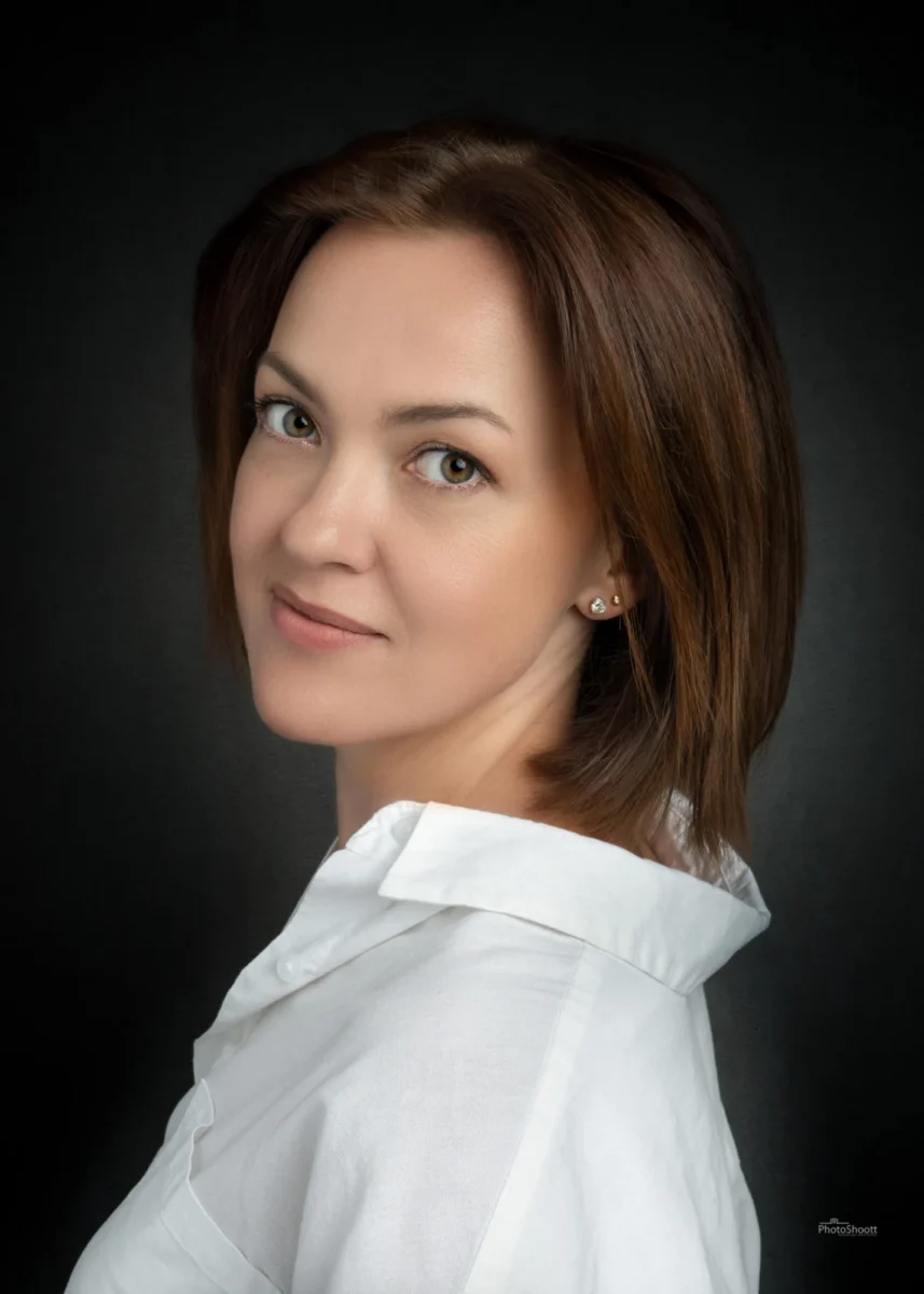Woman with auburn hair in a soft studio headshot on a dark backdrop