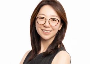 Woman with long dark hair and glasses smiling in a bright headshot, New Jersey